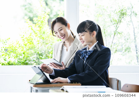 Junior high school girls and female teachers studying on tablet PCs Junior high school girls and female teachers studying on tablet PCs 109608344
