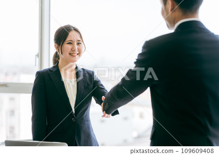 男性和女性商人（律師、稅務會計師、會計師）在簽署商業協議時握手 109609408