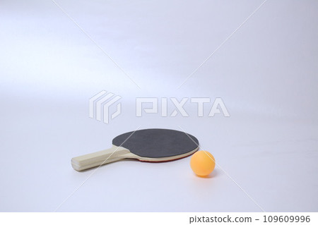 一個乒乓球拍，黑色面朝上位於螢幕中央，右側前面有一個橘色乒乓球，白色背景 2 109609996