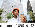 Happy black woman in helmet standing with coffee cup in daylight 109610142