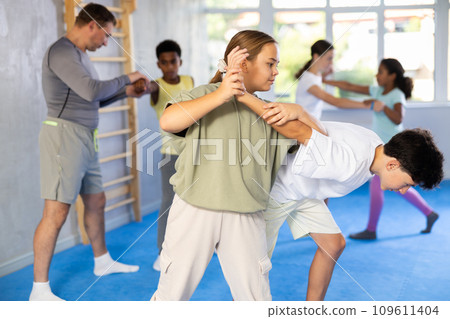 Tween girl practicing armlock in sparring with boy during self-defense classes Tween girl practicing armlock in sparring with boy during self-defense classes 109611404