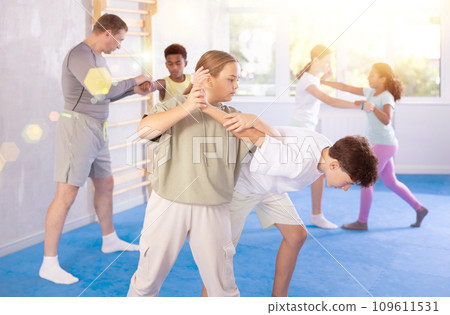 Tween girl practicing armlock in sparring with boy during self-defense classes 109611531