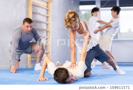 Teenagers practicing painful armlock in sparring during self defence training 109611571