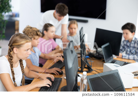 Preteen girl working with computer programs in training room 109611584