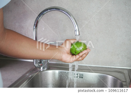 hand washing avocado with water sprinkling hand washing avocado with water sprinkling 109611617