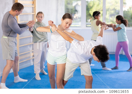 Preteen children pairs learning strength self-defense in gym Preteen children pairs learning strength self-defense in gym 109611655