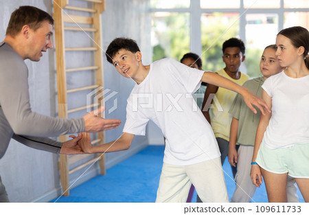 Self-defence course instructor demonstrating painful wristlock to teenagers Self-defence course instructor demonstrating painful wristlock to teenagers 109611733