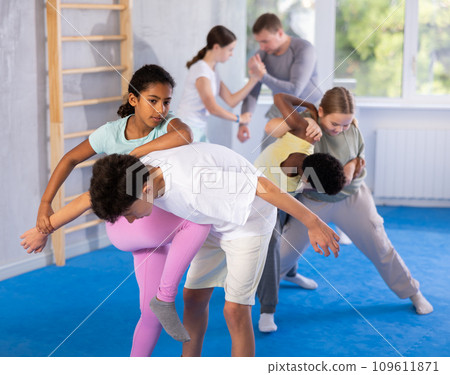 African teenage girl practicing wristlock with elbow and knee blows in sparring with boy 109611871