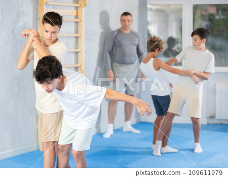 Teenagers practicing painful armlock in sparring at self defence training Teenagers practicing painful armlock in sparring at self defence training 109611979