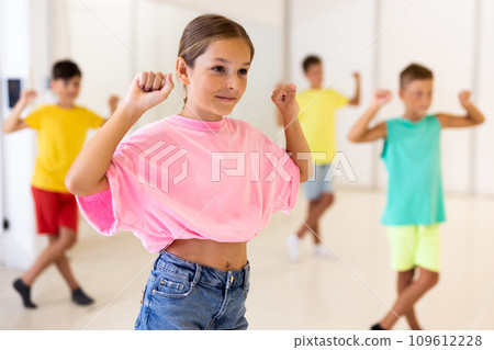 Cheerful preteen girl learning energetic dance in choreography class Cheerful preteen girl learning energetic dance in choreography class 109612228