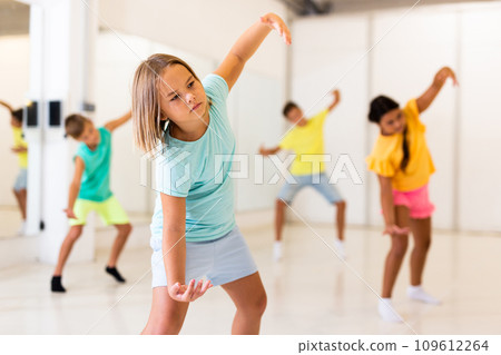 Girl together with other children, learns modern hip hop dance moves in class 109612264