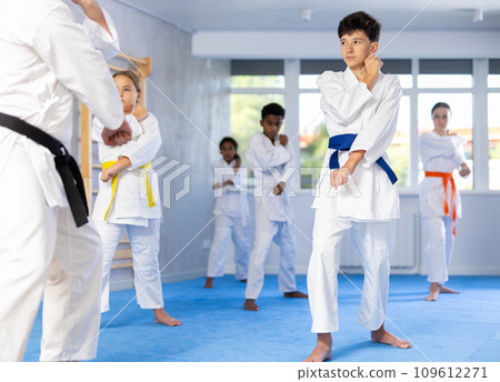 Determined tween boy practicing punches during group martial arts workout 109612271