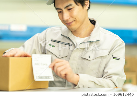 A male worker attaches a label to an outer box before shipping 109612440