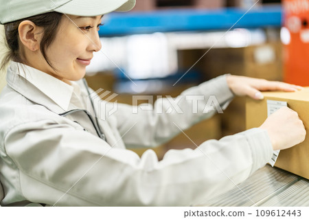 A female worker attaches labels to outer boxes before shipping 109612443