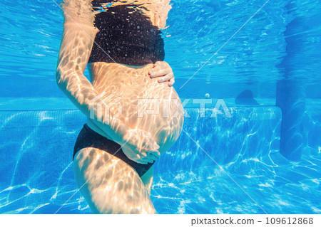 Pregnancy embraced underwater a tranquil scene as a woman tenderly hugs her belly in the pool, capturing the beauty of maternal connection Pregnancy embraced underwater a tranquil scene as a woman tenderly hugs her belly in the pool, capturing the beauty of maternal connection 109612868