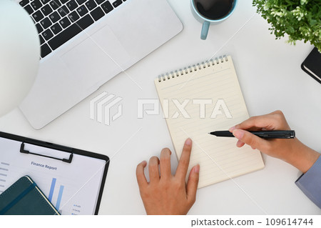 Above view of businesswoman working on laptop computer and writing notes in notebook Above view of businesswoman working on laptop computer and writing notes in notebook 109614744