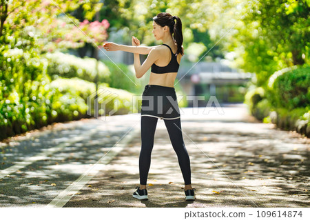 Young woman in sportswear stretching in the greenery 109614874