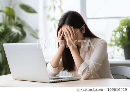 A woman officer at an office desk holds her head, possibly suffering from a migraine or office syndrome A woman officer at an office desk holds her head, possibly suffering from a migraine or office syndrome 109616419