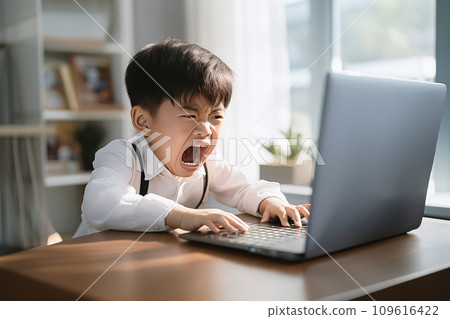 Gaming boy in white shirt appears frustrated or angry at a laptop screen, possibly due to a game challenging or computer issue 109616422