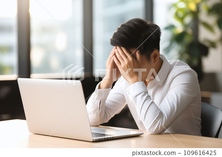 A man officer in a white shirt at an office desk holds his head, possibly suffering from a migraine or office syndrome A man officer in a white shirt at an office desk holds his head, possibly suffering from a migraine or office syndrome 109616425
