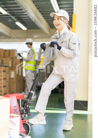 Female inventory manager moving pallets with a jack 109616682