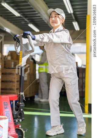 Female inventory manager moving pallets with a jack 109616683