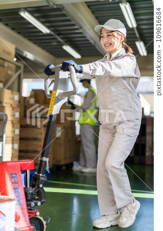 Female inventory manager moving pallets with a jack Female inventory manager moving pallets with a jack 109616684