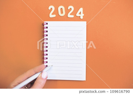 Top view of child hand with holding pen on white paper blank notebook and writing wish list. 109616790