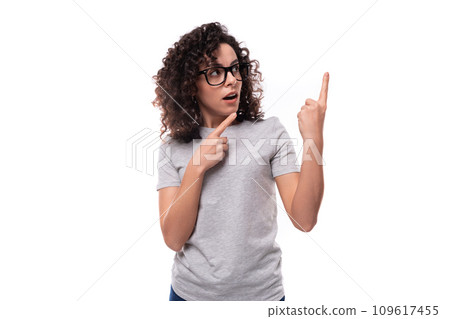 adorable slim curly brunette promoter woman with glasses dressed in gray basic t-shirt with logo 109617455