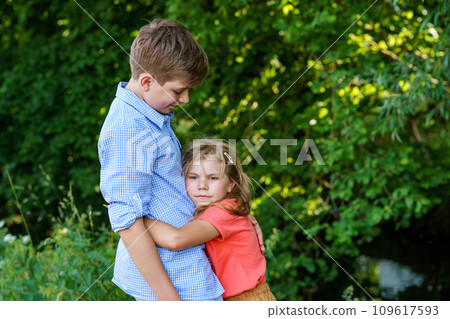 An upset little girl finds comfort in the embrace of her caring teenage brother, exemplifying the bond of a loving family. Loving Siblings, Brother and Sister. 109617593