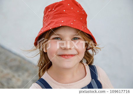 Portrait of happy smiling preschool girl outdoors. Little child with blond hairs looking and smiling at the camera. Happy healthy child enjoy outdoor activity and playing. 109617716