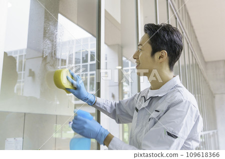 A male cleaner cleaning windows in an office. Photography cooperation: Ariake College of Education and Arts A male cleaner cleaning windows in an office. Photography cooperation: Ariake College of Education and Arts 109618366