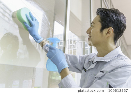 A male cleaner cleaning windows in an office. Photography cooperation: Ariake College of Education and Arts 109618367