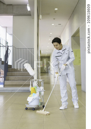 Male cleaning worker wiping the floor in an office building, vertical position. Photography cooperation: Ariake College of Education and Arts 109618609