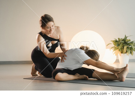 Mom and teenage daughter do gymnastics together in the fitness room. A woman and a girl train in the gym Mom and teenage daughter do gymnastics together in the fitness room. A woman and a girl train in the gym 109619257