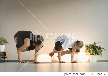 Mom and teenage daughter do gymnastics together in the fitness room. A woman and a girl train in the gym 109619267