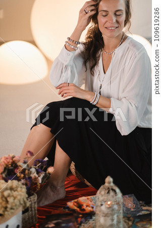 Women's circle and practice in the use of metaphorical cards. The girl is sitting surrounded by flowers Women's circle and practice in the use of metaphorical cards. The girl is sitting surrounded by flowers 109619286