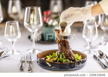 The chef or waiter finishes the meal right on the restaurant table, pouring the sauce over the leg of lamb confit 109619846