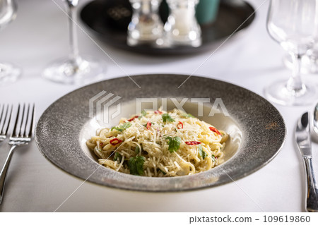 Italian Spaghetti Algio e Olio with Garlic Parmesan and chili peppers on restaurant festive table Italian Spaghetti Algio e Olio with Garlic Parmesan and chili peppers on restaurant festive table 109619860