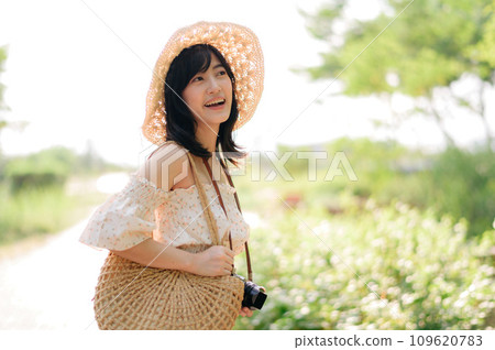 Portrait of asian young woman traveler with weaving hat and basket and a camera on green public park nature background. Journey trip lifestyle, world travel explorer or Asia summer tourism concept. Portrait of asian young woman traveler with weaving hat and basket and a camera on green public park nature background. Journey trip lifestyle, world travel explorer or Asia summer tourism concept. 109620783