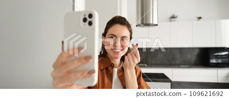 Beautiful young woman, social media blogger recording video, online video chatting on smartphone, standing at home with mobile phone 109621692