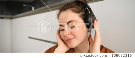 Close up shot of modern stylish woman in headphones, relaxes while listens to music in wireless earphones 109622316