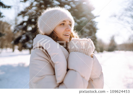 Young woman in winter style clothes walking in the snowy park. Winter fashion, holidays. Young woman in winter style clothes walking in the snowy park. Winter fashion, holidays. 109624453