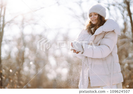 Young woman in winter style clothes walking in the snowy park. Winter fashion, holidays. Young woman in winter style clothes walking in the snowy park. Winter fashion, holidays. 109624507