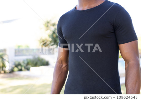 Mid section of african american man in black t-shirt with copy space in garden 109624543