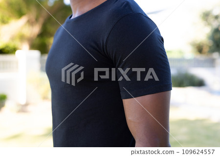 Mid section of african american man in black t-shirt with copy space in garden Mid section of african american man in black t-shirt with copy space in garden 109624557