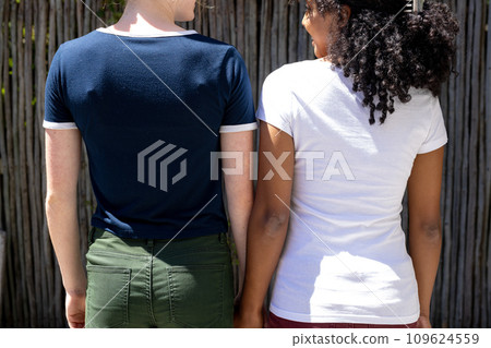 Diverse women in white and blue t-shirt with white trims and copy space on wooden background Diverse women in white and blue t-shirt with white trims and copy space on wooden background 109624559