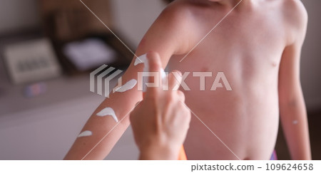 Mother applying sunscreen to baby skin closeup 109624658