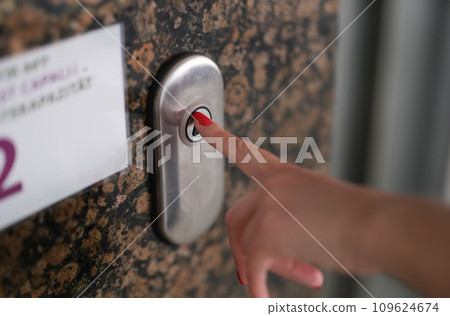 Female finger with red manicure pressing elevator button closeup Female finger with red manicure pressing elevator button closeup 109624674