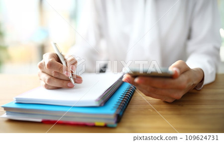 Closeup of freelancer hands with mobile phone working on finance 109624731